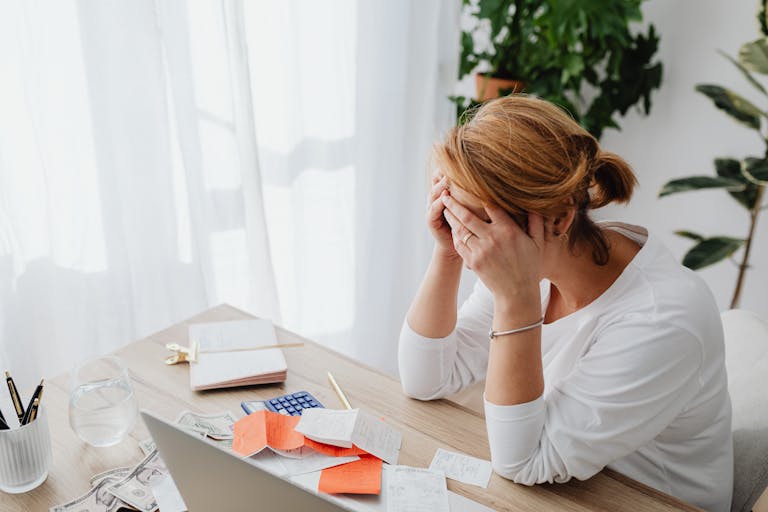 Woman stressed over financial mistakes at a desk, dealing with expenses and calculations.